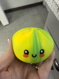 Yellow squishy toy with a face held in a hand against a kitchen background