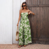 Woman wearing a green and white strapless jumpsuit standing against a wooden door.
