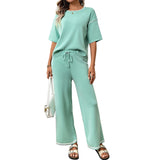Woman wearing a mint green outfit with wide-leg pants on a white background