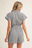 Woman wearing a black and white striped romper on a beige background