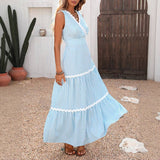 Woman wearing a blue and white striped dress standing outdoors with a wooden gate and cacti in the background.