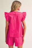 Woman wearing a bright pink outfit with ruffled sleeves on a plain background