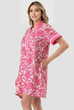 Woman wearing a pink and white patterned dress on a light gray background