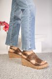 Brown sandals worn with blue jeans on a neutral background
