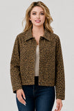 A woman modeling a cropped leopard-print jacket with a collar and front pockets, worn over a light top and dark blue jeans, against a plain light gray studio background.