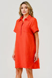 Woman wearing an orange dress with a collar on a plain background