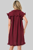 A woman shown from the back wearing a short-sleeve burgundy dress with ruffled trim at the collar and sleeves, photographed against a plain light gray studio background.