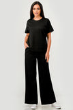 Woman wearing a black outfit with wide-leg pants on a white background
