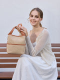 Woman sitting on a bench holding a woven handbag against a plain background