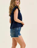 Woman wearing a navy sleeveless top and denim skirt on a beige background