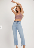 Woman wearing a mauve crop top and light blue jeans on a white background