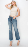Woman wearing a white sleeveless top and blue jeans against a white background