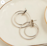 Silver hoop earrings on a white plate with gold rim