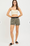 Woman wearing a white crop top and leopard print shorts on a white background