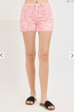 Person wearing pink floral shorts on a white background
