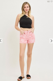 Woman wearing a black halter top and pink shorts on a white background