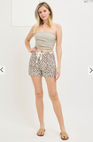 Woman wearing a strapless top and leopard print shorts on a white background