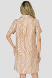 Woman wearing a beige dress with leaf pattern on a plain background