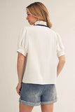 Woman wearing a white blouse and denim shorts on a plain background
