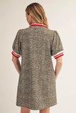 Woman wearing a patterned dress with red and white trim on a plain background
