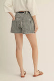 Person wearing black and white striped shorts on a beige background