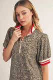 Woman wearing a leopard print dress with red and white accents on a plain background