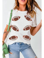 Woman wearing a white t-shirt with football designs, paired with blue jeans and a green handbag.