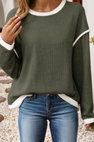 Green sweater with white trim worn by a person on a neutral background