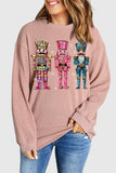 Person wearing a pink sweatshirt with colorful nutcracker design on a plain background