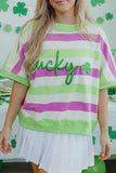 Person wearing a striped shirt with 'lucky' and shamrock design, standing in front of a St. Patrick's Day-themed background.