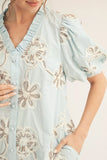 Light blue blouse with floral embroidery on a neutral background