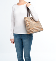 Person holding a plaid tote bag against a white background