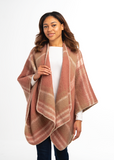 Woman wearing a pink plaid poncho over a white shirt and jeans on a white background