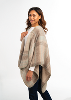Woman wearing a beige poncho over a white shirt on a white background