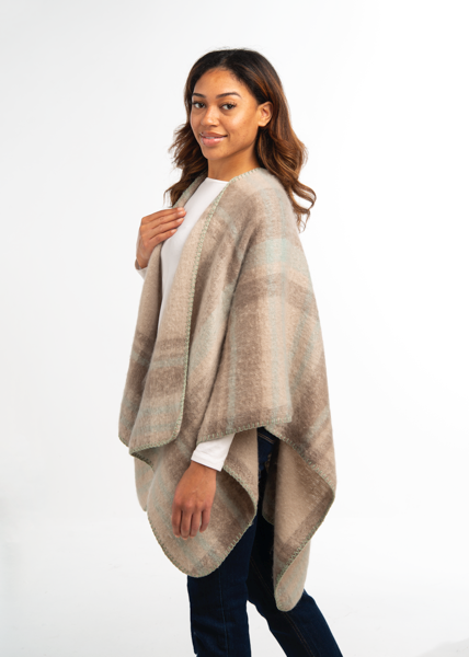 Woman wearing a beige poncho over a white shirt on a white background