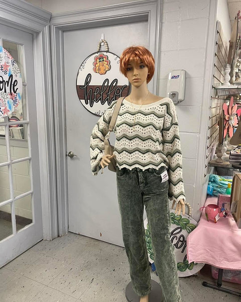 Mannequin wearing a patterned sweater and jeans in a store setting.