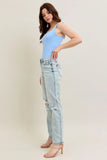 Woman wearing a light blue tank top and distressed jeans on a plain background