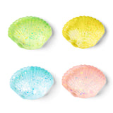Four small scallop-shaped squishies with glittery speckles, arranged in a 2x2 grid on a white background. The colors are light green, pale yellow, light blue, and light pink.