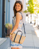 Woman holding a woven handbag on a sidewalk