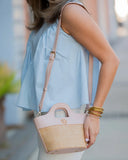 Person holding a pink and beige handbag with a blurred background